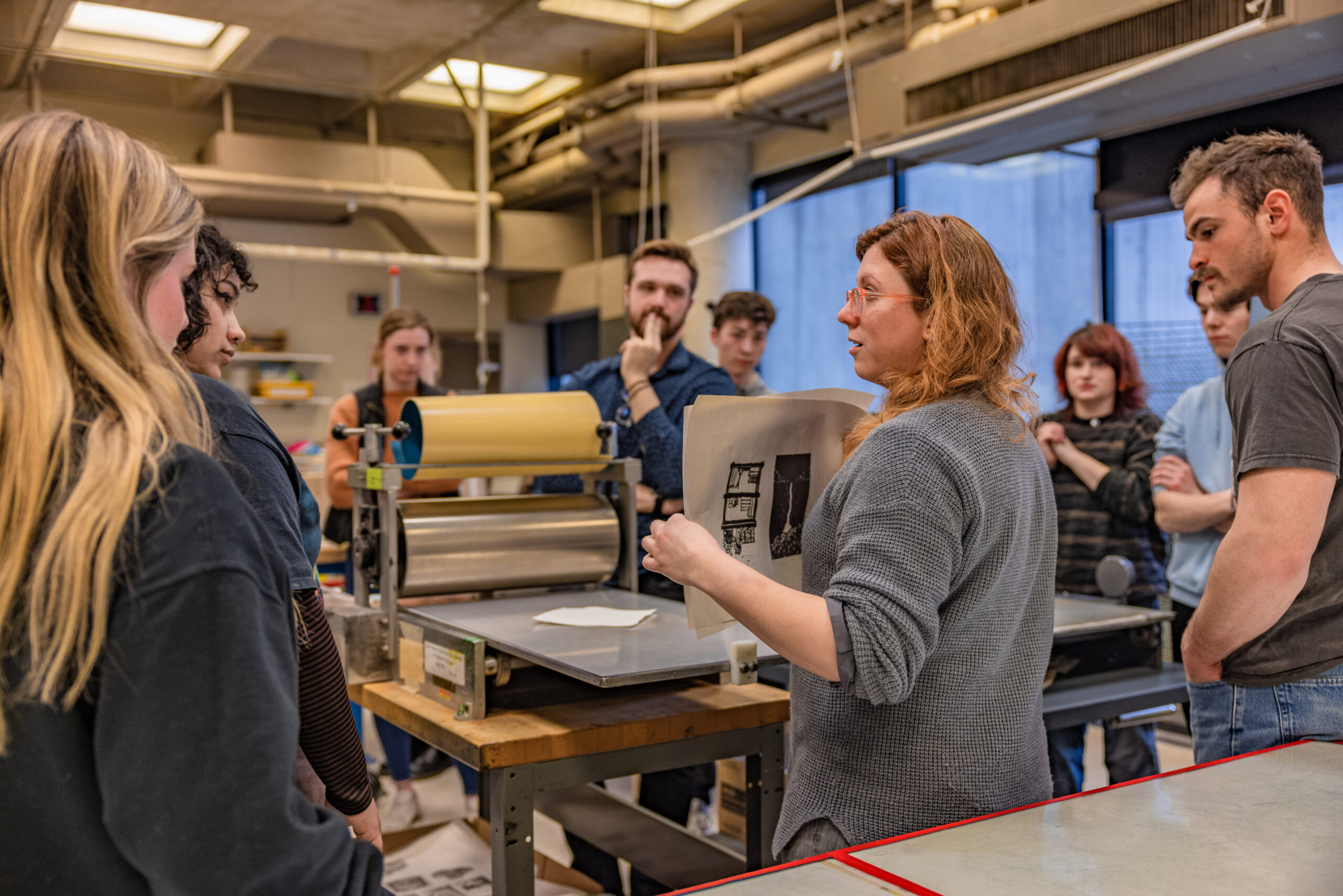 Professor teaching students' printmaking in workshop.