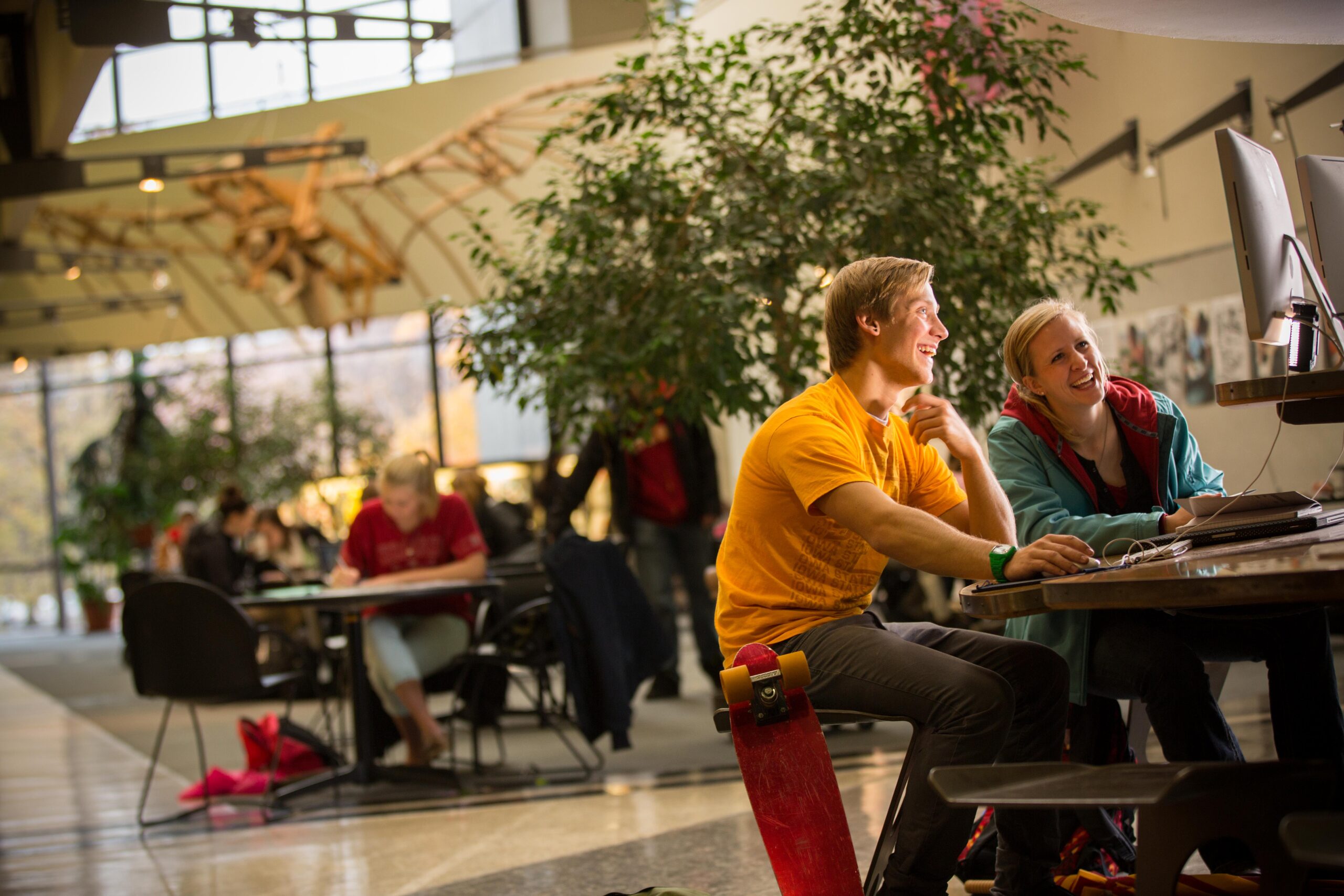 Two students conversing in the College of Design atrium.