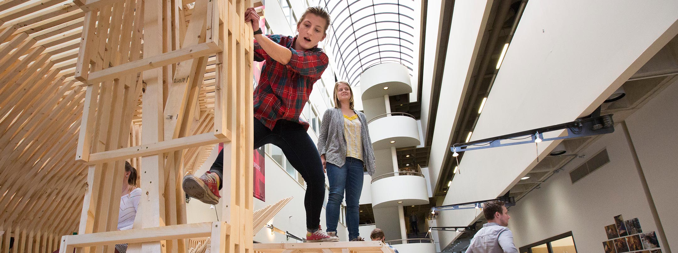 A child and adult explore wooden sculpture created by architecture student, located in the College of Design atrium.